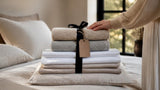 Pile de linge de maison neuf sur un lit, draps et serviettes en coton : bien choisir son linge au Black Friday