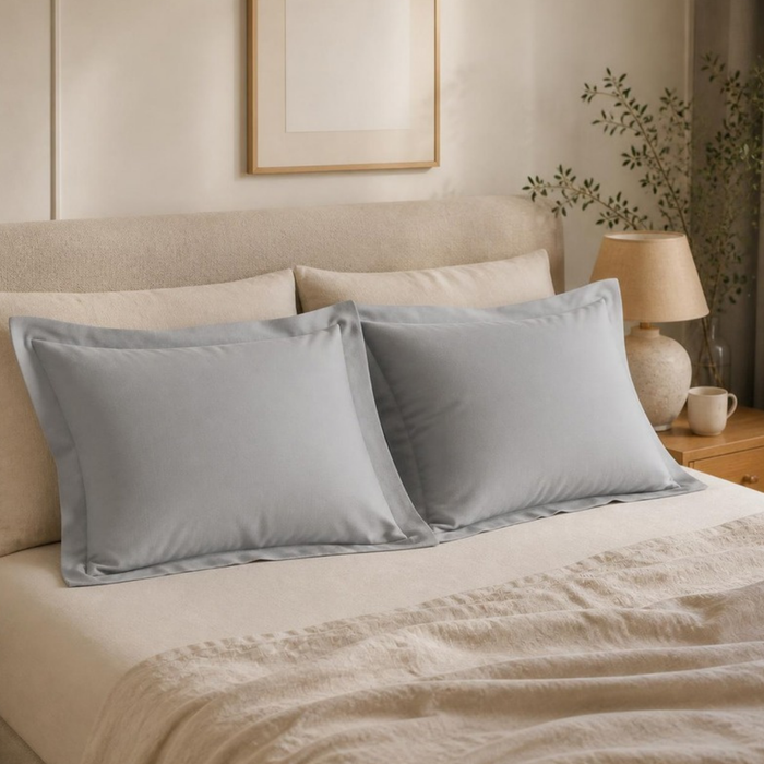 Duo d'oreillers flocons JLB Home habillés de taies en percale 80 fils gris clair sur un lit en linge écru